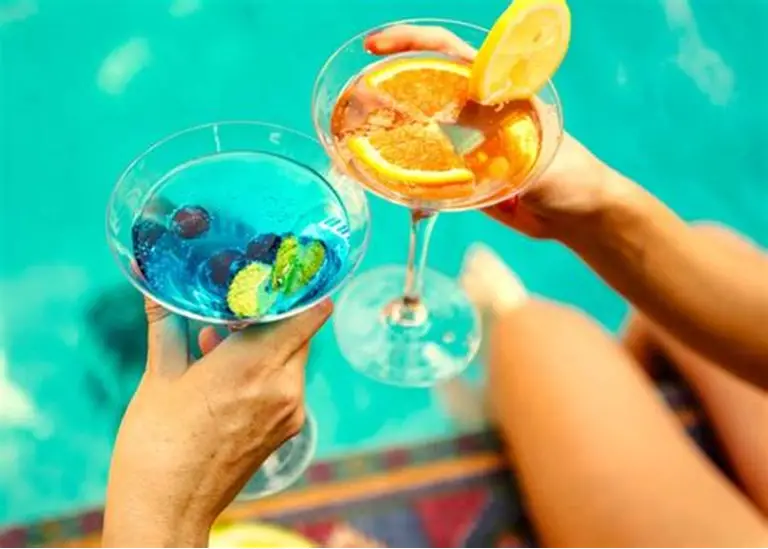 Pool Party Cocktails - Group of friends toasting with colorful cocktails in the pool